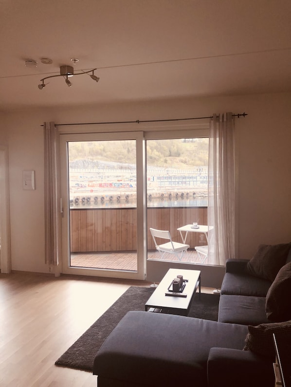 A living room with a sofa, a coffee table, and a view of a wooden deck and outdoor area.