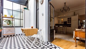 A modern kitchen with white cabinets, a wooden dining table, and a black and white checkered floor. - Philbeach Balcony- 2bed flat in Earls Ct (London)