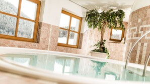 Piscina interna com vista para montanhas nevadas através de grandes janelas.