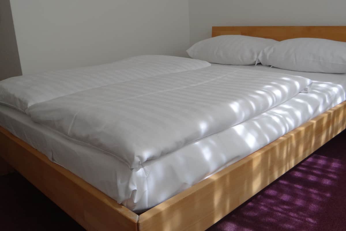 A neatly made bed with a wooden frame and white bedding.