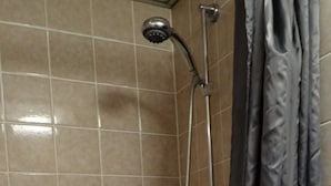 A shower area with a handheld showerhead, a wall-mounted showerhead, and a shower control panel. - Hotel Meesenburg (Würzburg)