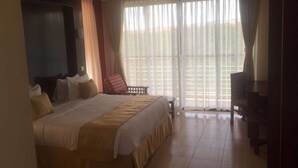 A hotel room with a large bed, a chair, and a desk. - Regency Mount Kenya Hotel (Ethi)