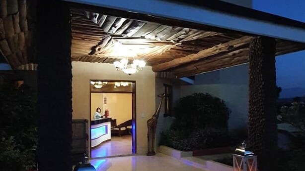 A hotel entrance with a covered patio, a reception desk, and a decorative giraffe statue. - Regency Mount Kenya Hotel (Ethi)