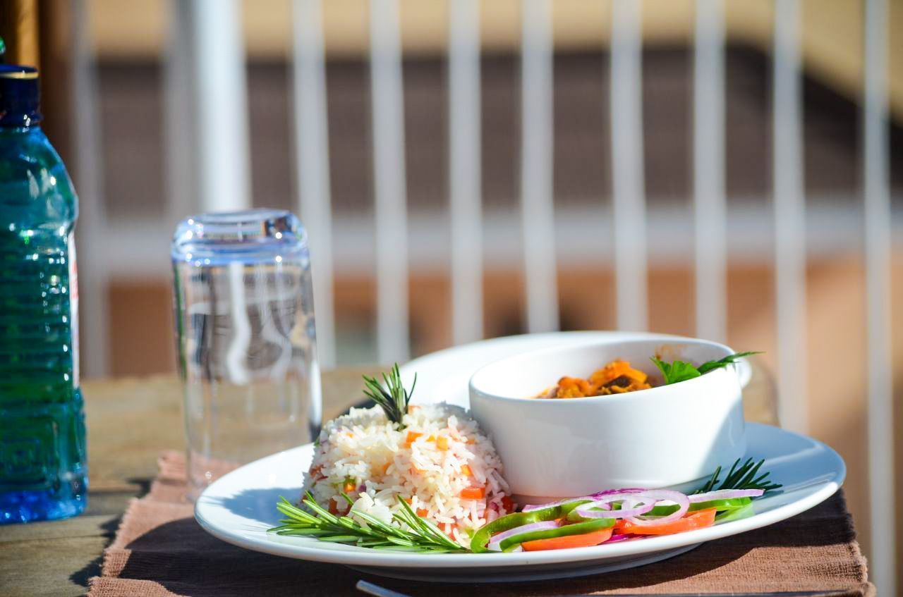 A plate of food with rice, vegetables, and a bowl of soup on a table.