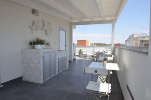 Un espacio al aire libre cubierto con una mesa, sillas, una planta en maceta y una pared de piedra.
