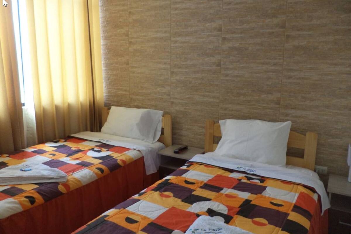 Two single beds with colorful quilts, wooden headboards, and white pillows.