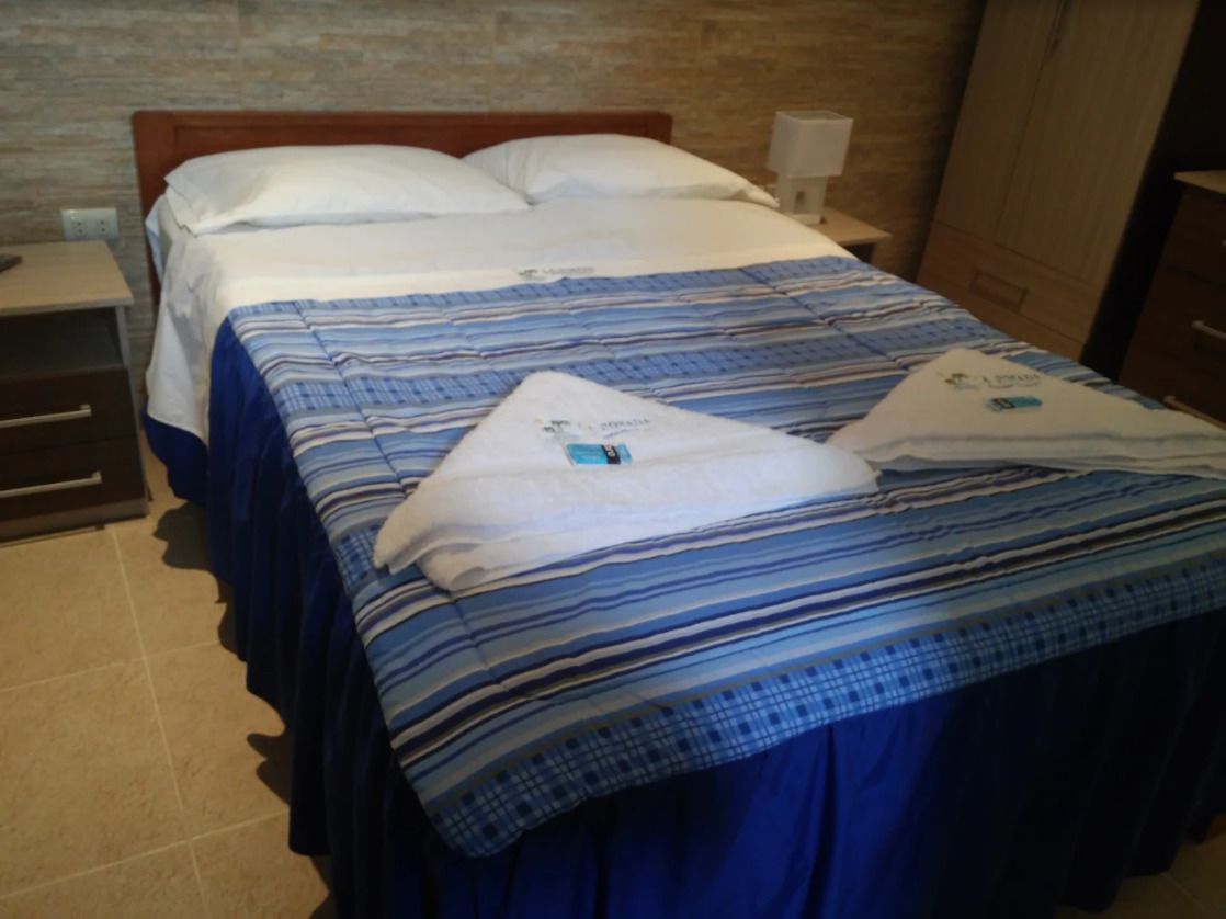 Una habitación de hotel con cama, mesita de noche, lámpara y armario.