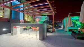 An outdoor patio area with a bar setup, seating, and a pool area. - Valentina Beach (Las Palmas de Gran Canaria)