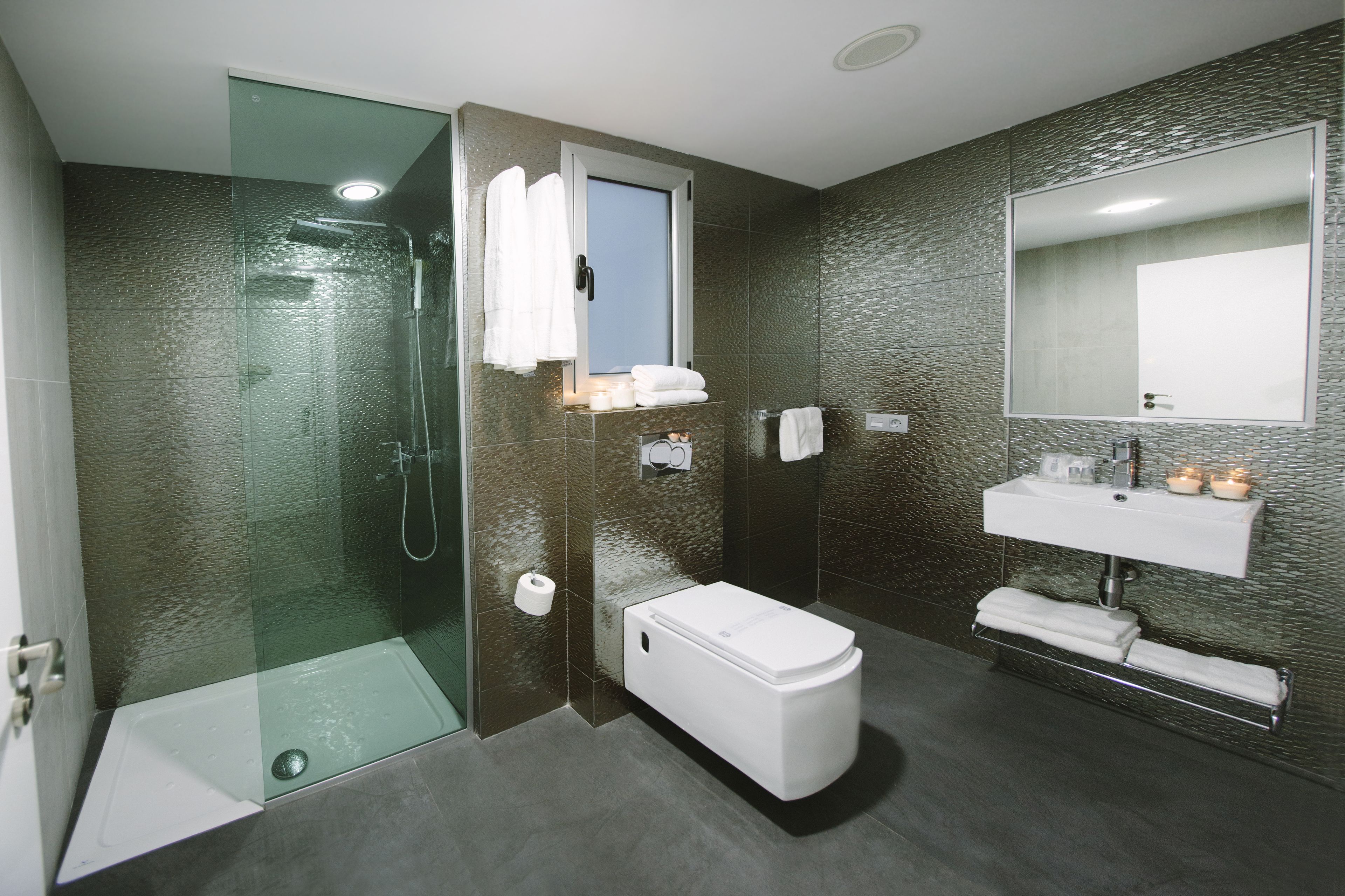 Ein modernes Badezimmer mit einer begehbaren Glasdusche, einer Toilette und einem Waschbecken mit Spiegel.