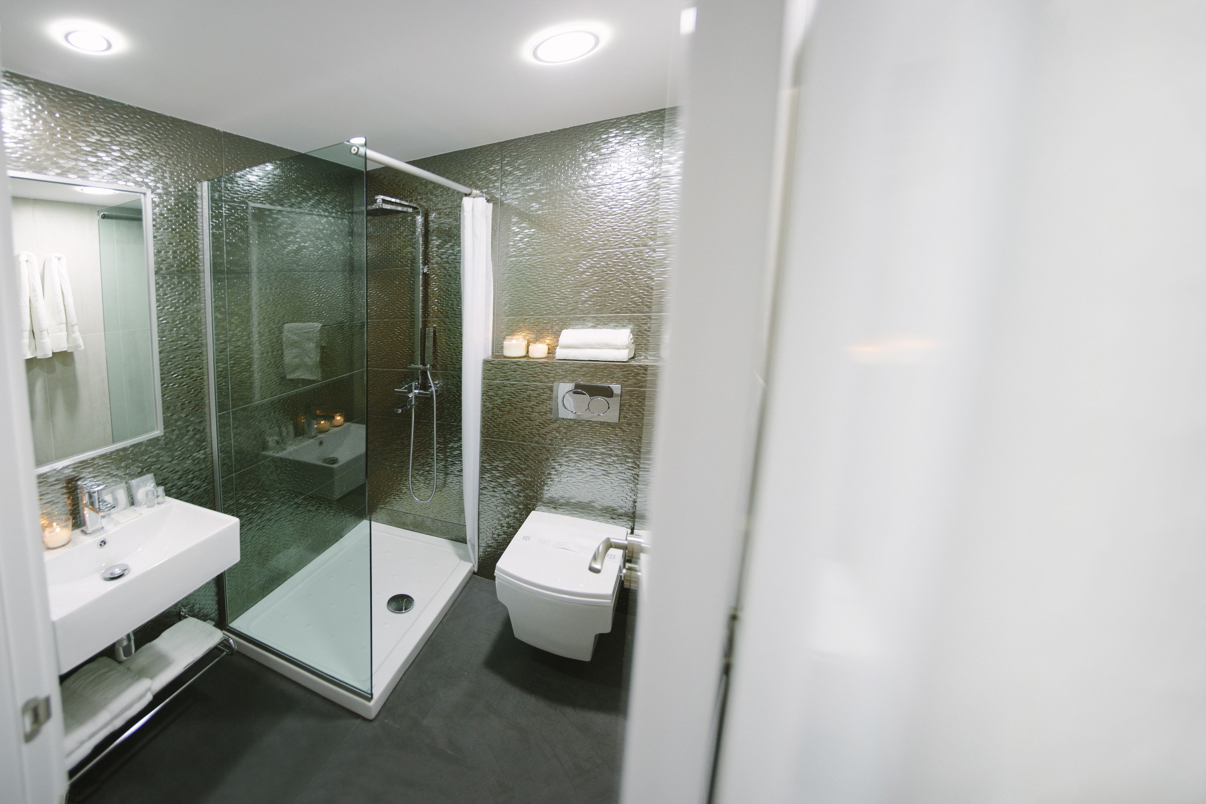Ein modernes Badezimmer mit einer Duschkabine aus Glas, einem weißen Waschbecken und einer Toilette.