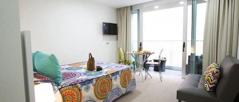 Ein modernes Hotelzimmer mit Bett, Sofa, kleinem Tisch und Fernseher.