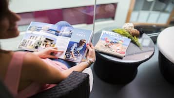 A person reading a travel brochure with images of a coastal town and a magazine titled "GRAN CANARIA".