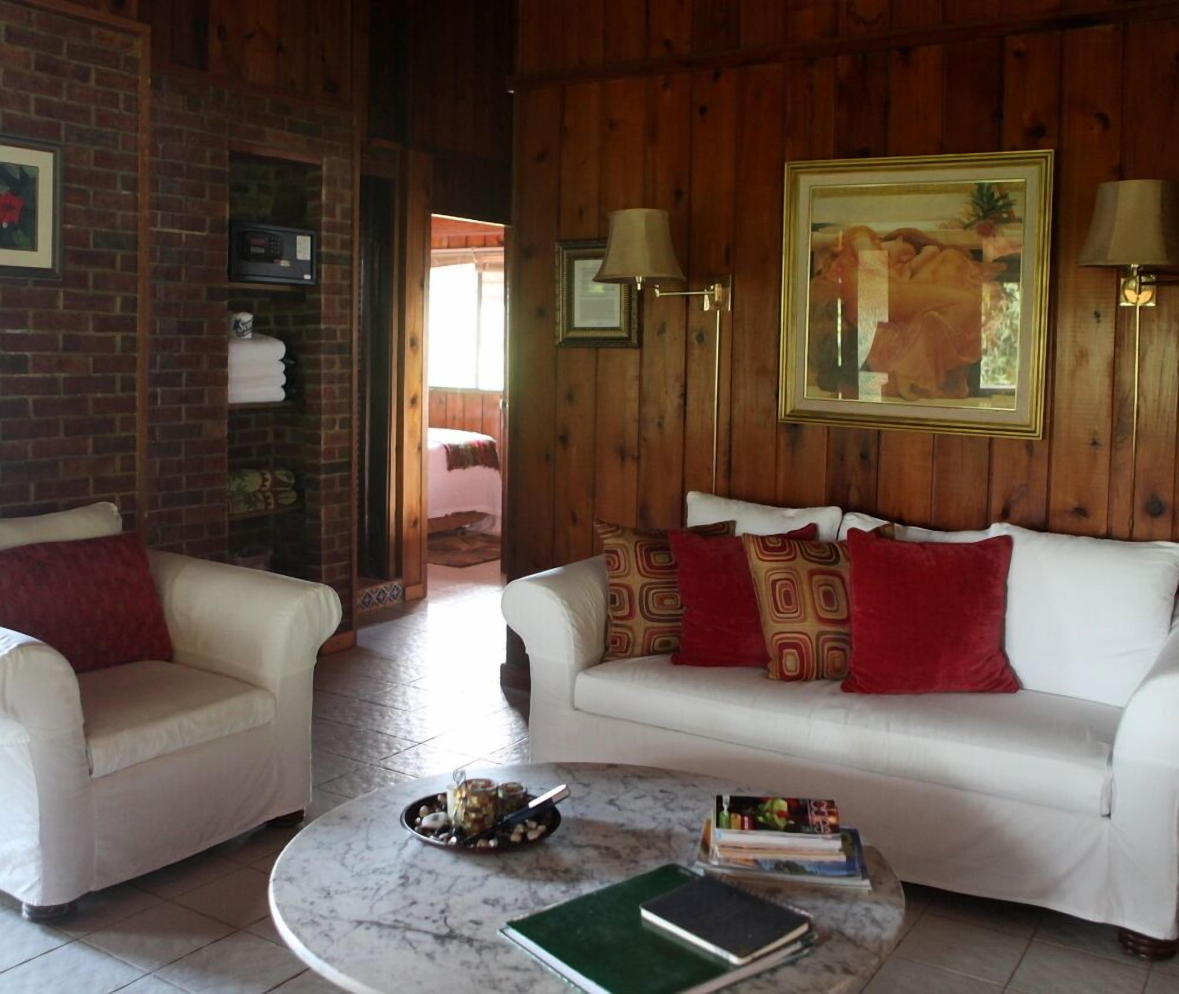 A cozy living room with a white sofa, two armchairs, a marble coffee table, and a painting on the wall.