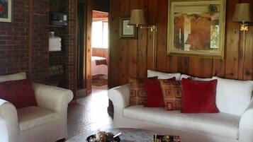 A cozy living room with a white sofa, two armchairs, a marble coffee table, and a painting on the wall.
