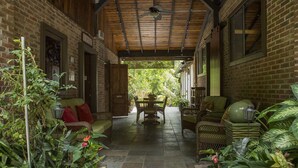 A covered patio with a brick wall, a wooden ceiling, and a table with chairs.