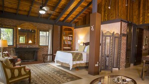 A cozy room with a fireplace, a bed, a bookshelf, and a coffee table.