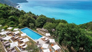 An aerial view of a resort with a swimming pool surrounded by lounge chairs and umbrellas, overlooking a turquoise sea and green hills. - Sesta Terra Natural Resort (Framura)