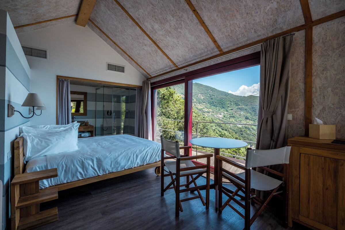 Ein Schlafzimmer mit einem Bett, einem Schreibtisch und Blick auf eine Berglandschaft.