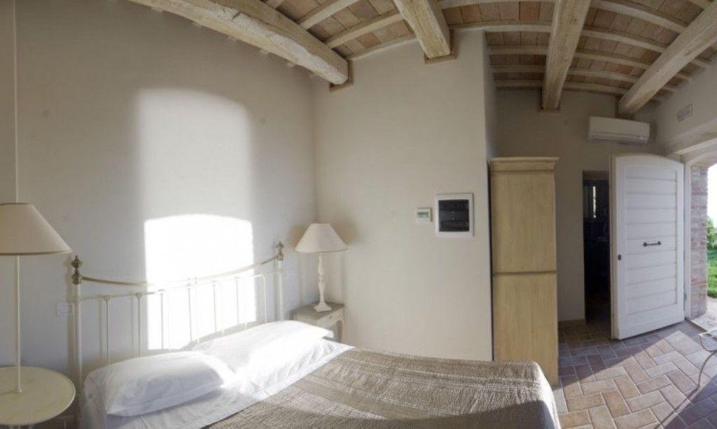 A bedroom with a bed, bedside lamps, a wardrobe, and a door leading outside.
