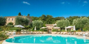 A pool area with lounge chairs and umbrellas, surrounded by trees and a building in the background. - Pamperduto Country Resort (Potenza Picena)