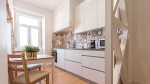 Una cocina moderna con armarios blancos, una mesa de comedor de madera y una planta en maceta.