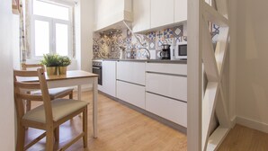 Una cocina moderna con armarios blancos, una mesa de comedor de madera con sillas y una ventana con cortinas.