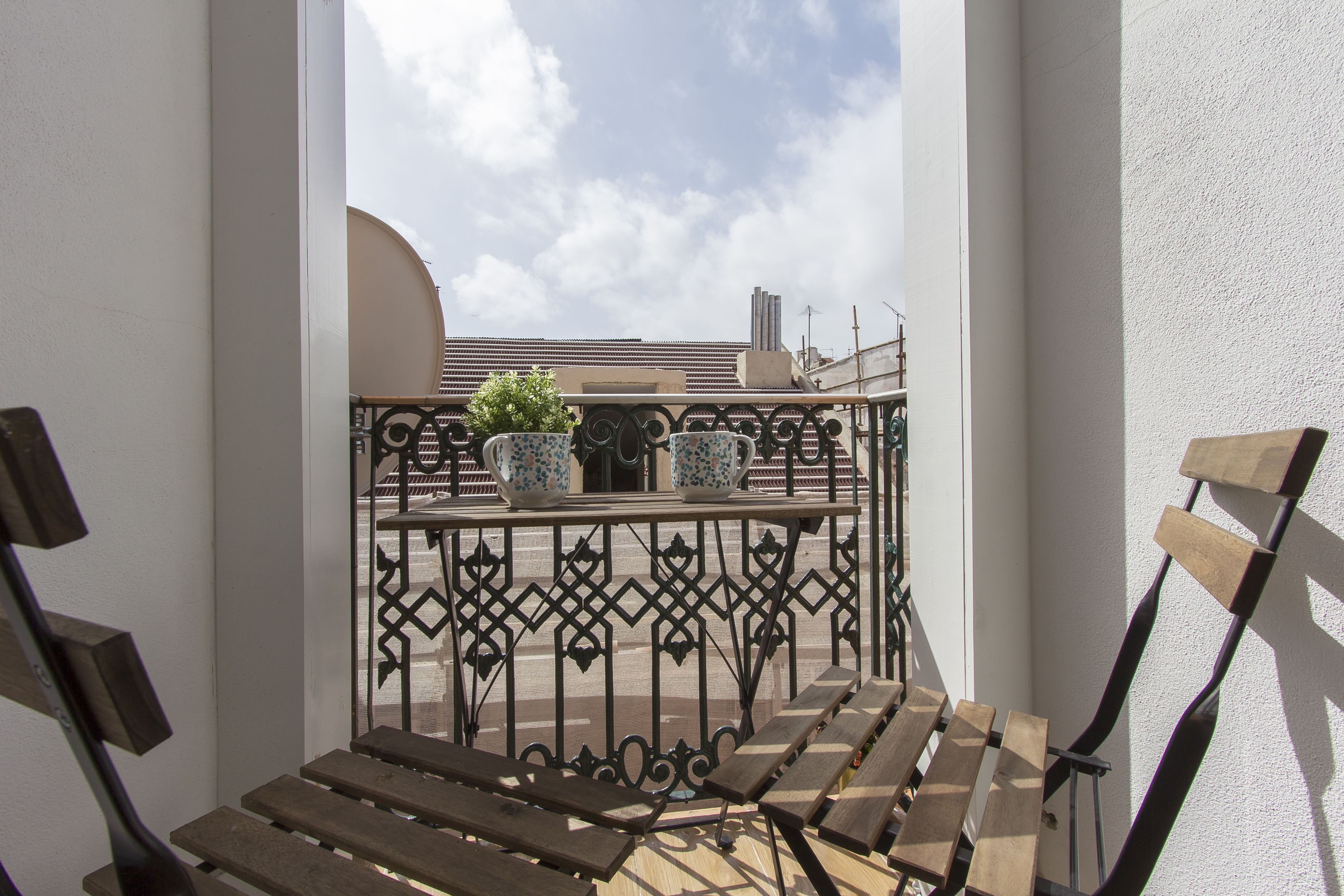A balcony with wooden benches and two potted plants.