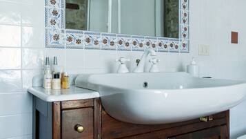 A bathroom with a white sink, wooden cabinet, and a decorative tile border.