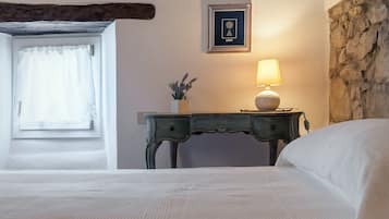 A bedroom with a bed, a nightstand with a lamp, a framed certificate on the wall, and a window with curtains.