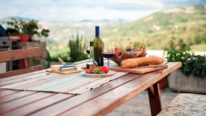 A wooden table set with a bottle of wine, a glass, a loaf of bread, and a bowl of fruit. - Fattoria Ca' di Fatino (Castiglione dei Pepoli)