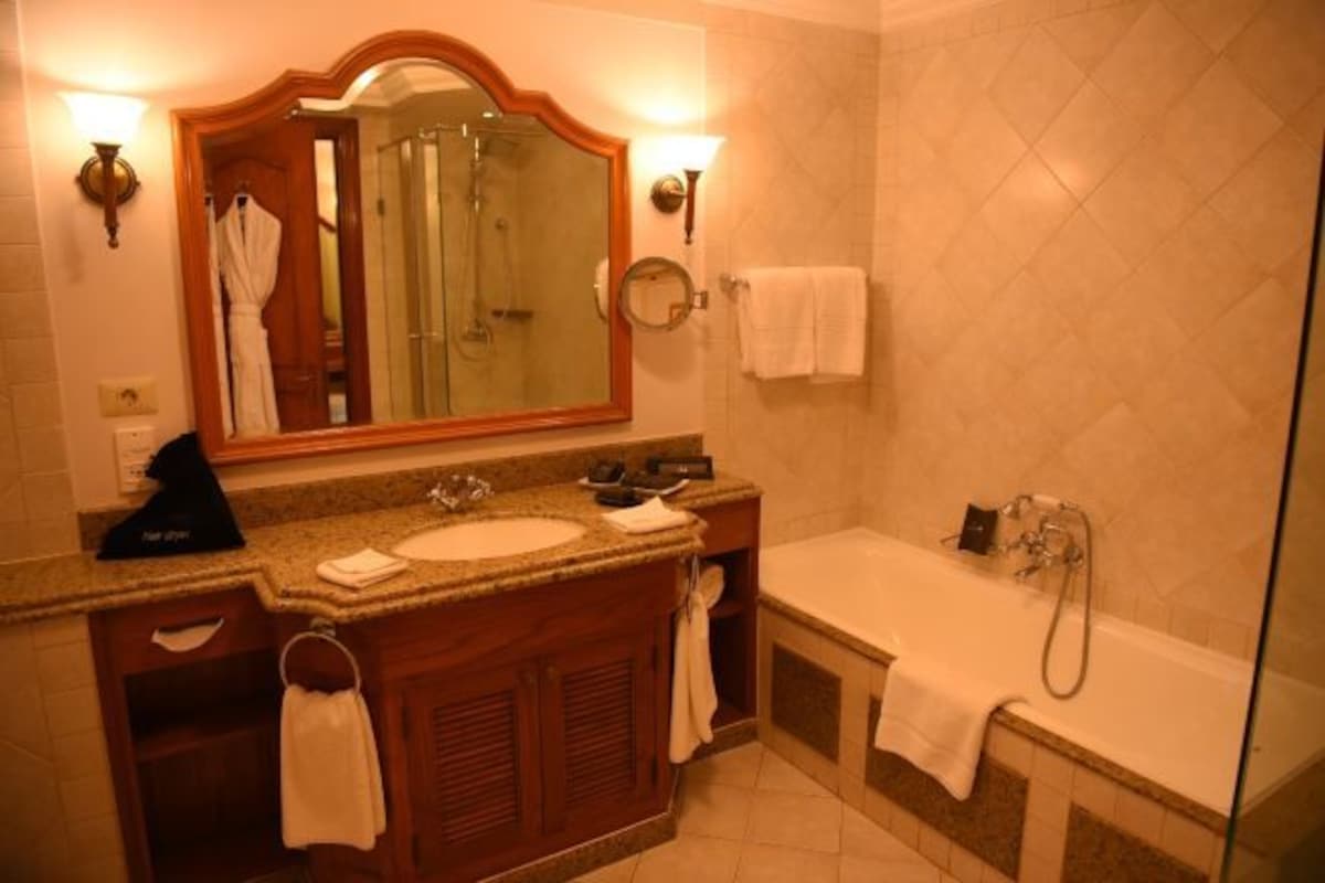 A bathroom with a sink, mirror, and bathtub.