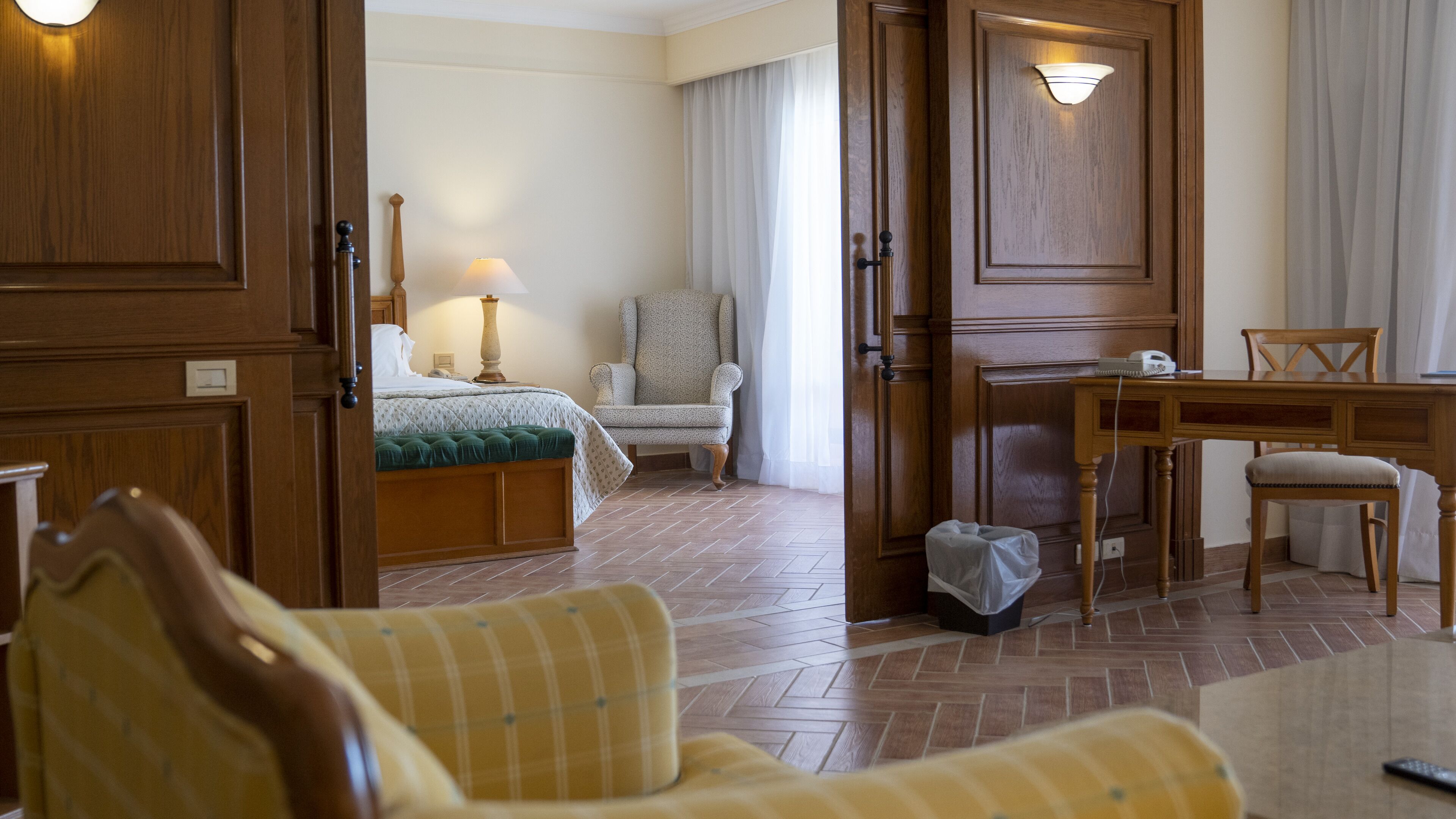 A hotel room with a bed, a chair, a desk, and a dining table.