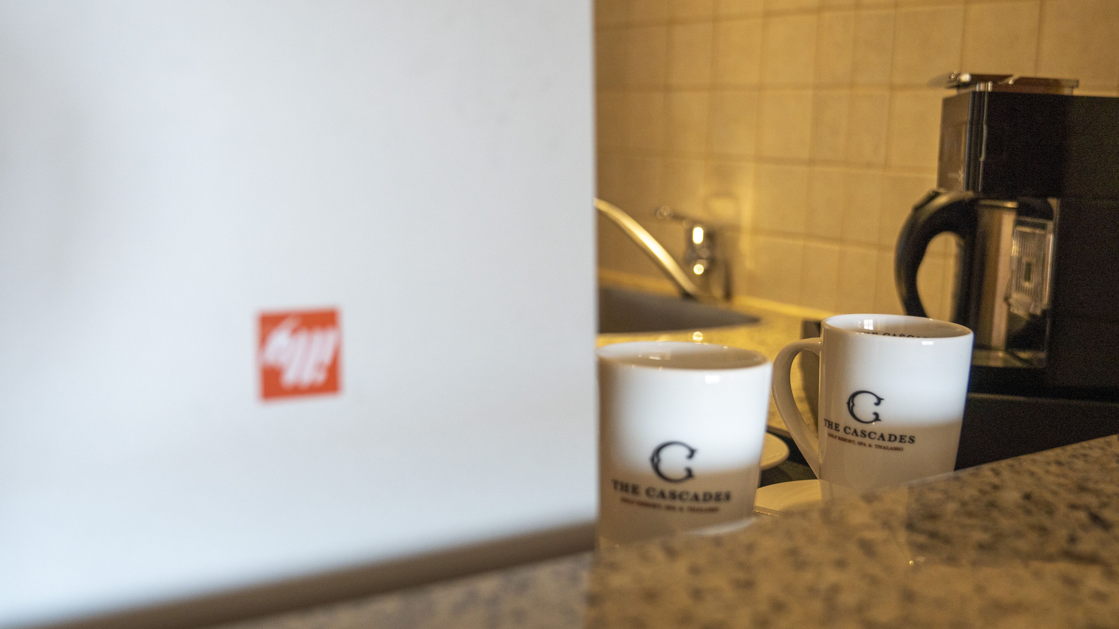 A kitchen counter with two white mugs labeled "The Cascades."
