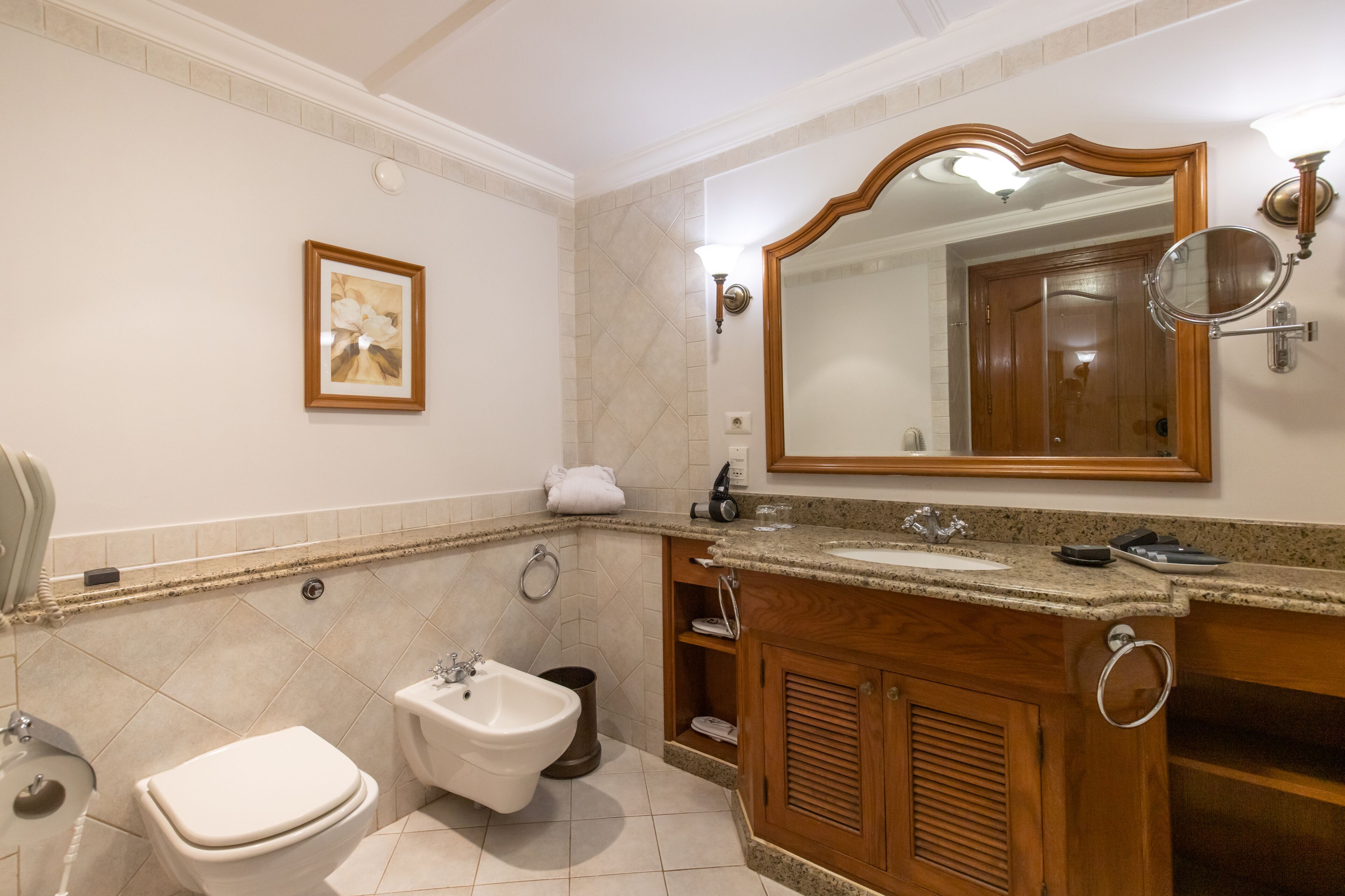 Une salle de bain équipée d’un bidet, d’un lavabo, d’un meuble-lavabo avec un miroir et d’un porte-serviettes.
