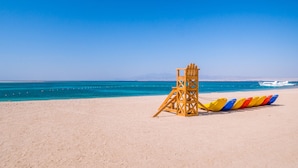 Une plage avec une tour de surveillance et une rangée de chaises de sauveteur aux couleurs vives.