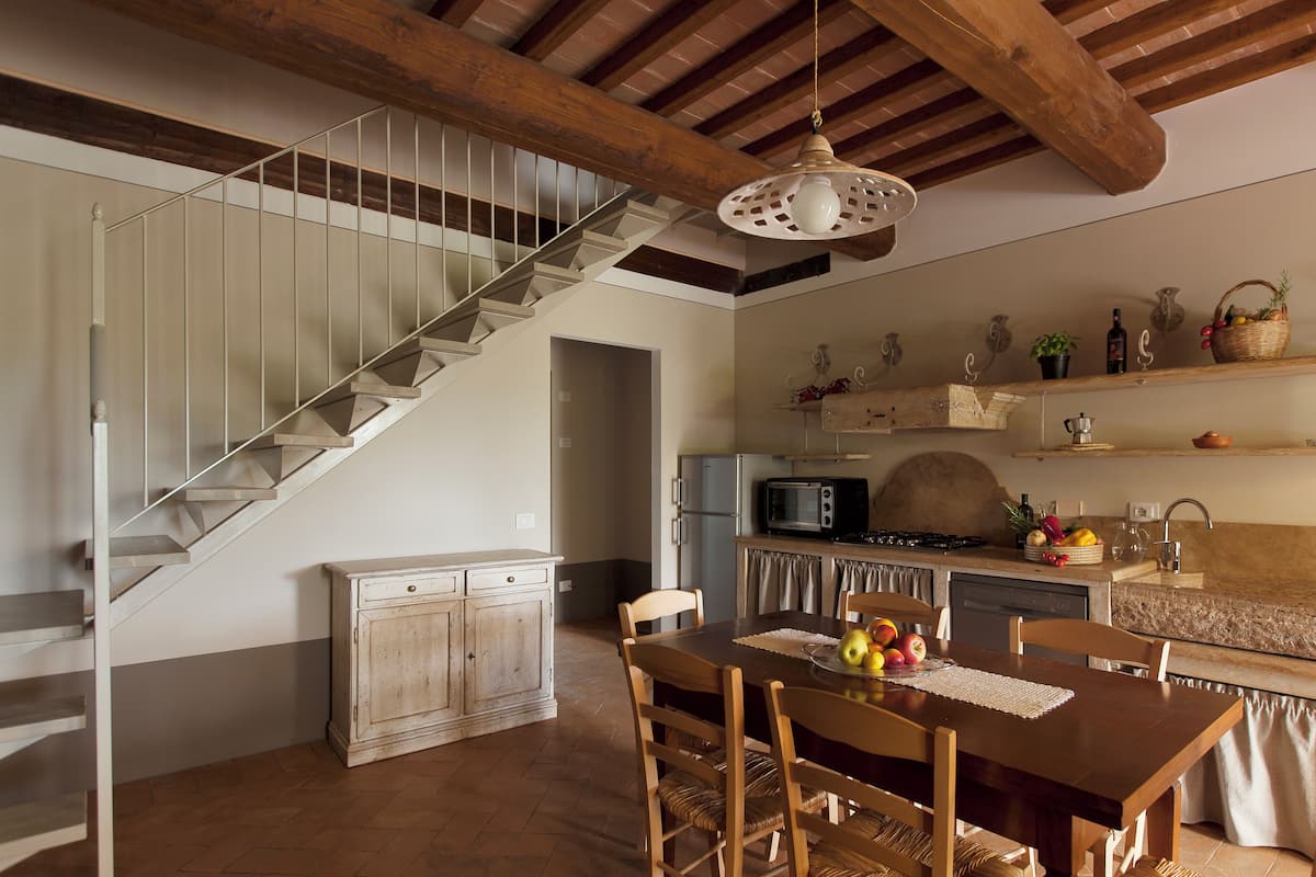 A kitchen with a wooden table, chairs, a microwave, and a sink.
