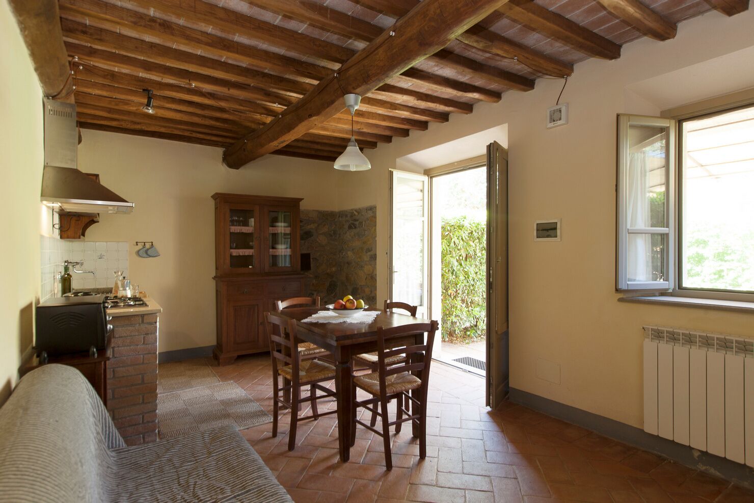 Una cocina rústica con una mesa de comedor, sillas de madera, un armario y una ventana.