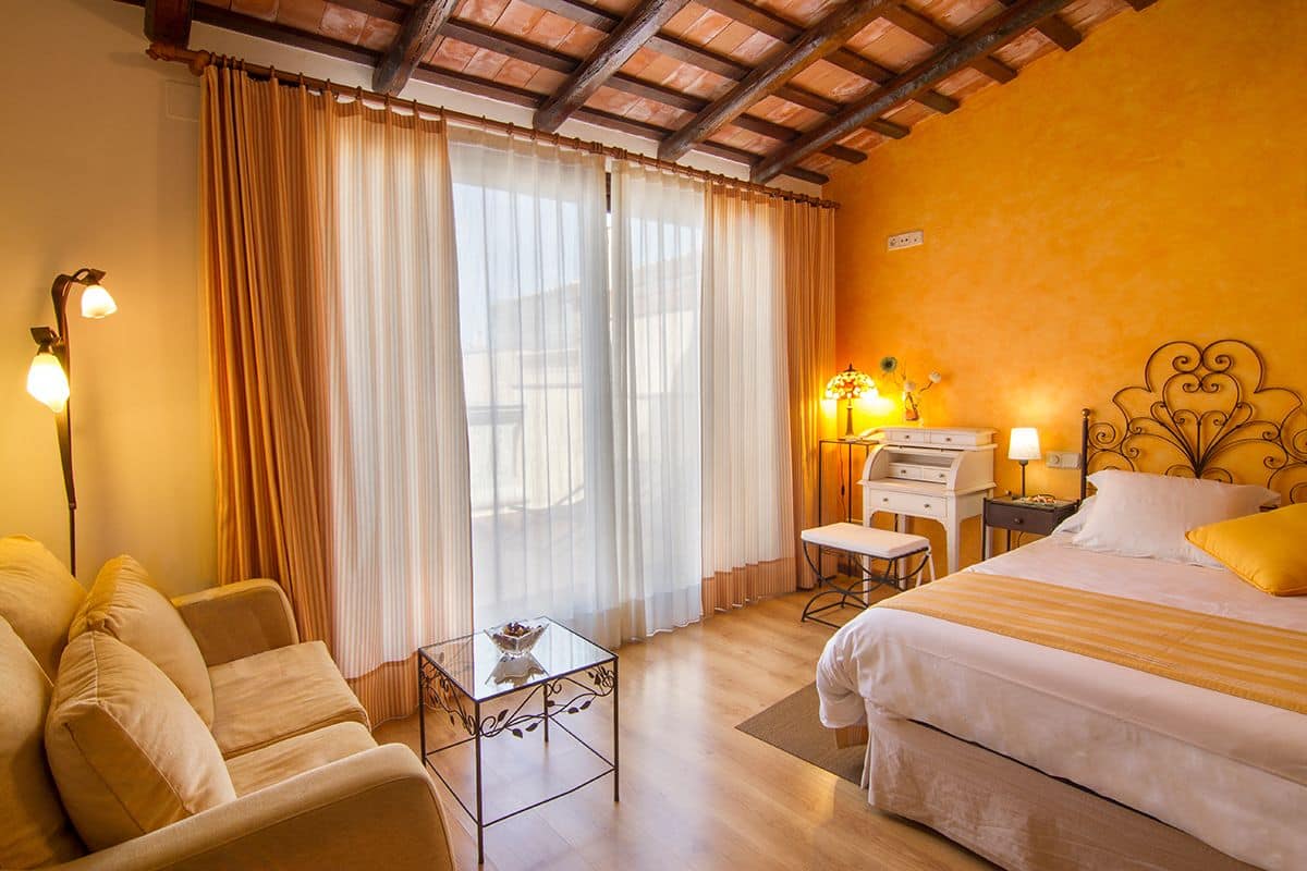 Habitació d'hotel amb un llit, un sofà, un escriptori i una làmpada.