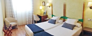 A hotel room with two beds, a desk, a chair, and a window with curtains. - Hotel Rosa (Begur)