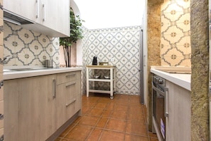 A compact kitchen with wooden cabinets, a small white shelf, and a tiled backsplash. - Downtown Classic by Homing (Lisbon)