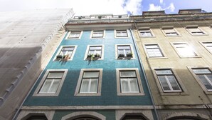 A multi-story building with a green facade, multiple windows, and balconies with metal railings.