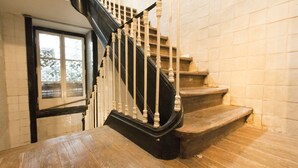 A wooden staircase with black balusters leading to a landing.