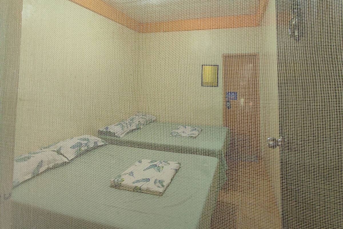A room with a bed covered by a patterned bedspread, a small table, and a chair.
