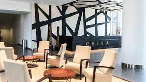 Un hall d’entrée moderne avec un comptoir d’accueil portant l’inscription « CEIBA », agrémenté d’un motif mural géométrique et de sièges contemporains.