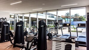 Une salle de sport équipée de divers appareils d’exercice, dotée de grandes fenêtres et offrant une vue sur l’extérieur.