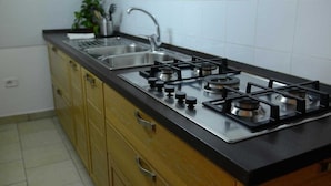 A kitchen with a gas stove, sink, and wooden cabinets. - B&B La Torretta di Chiaia (Naples)