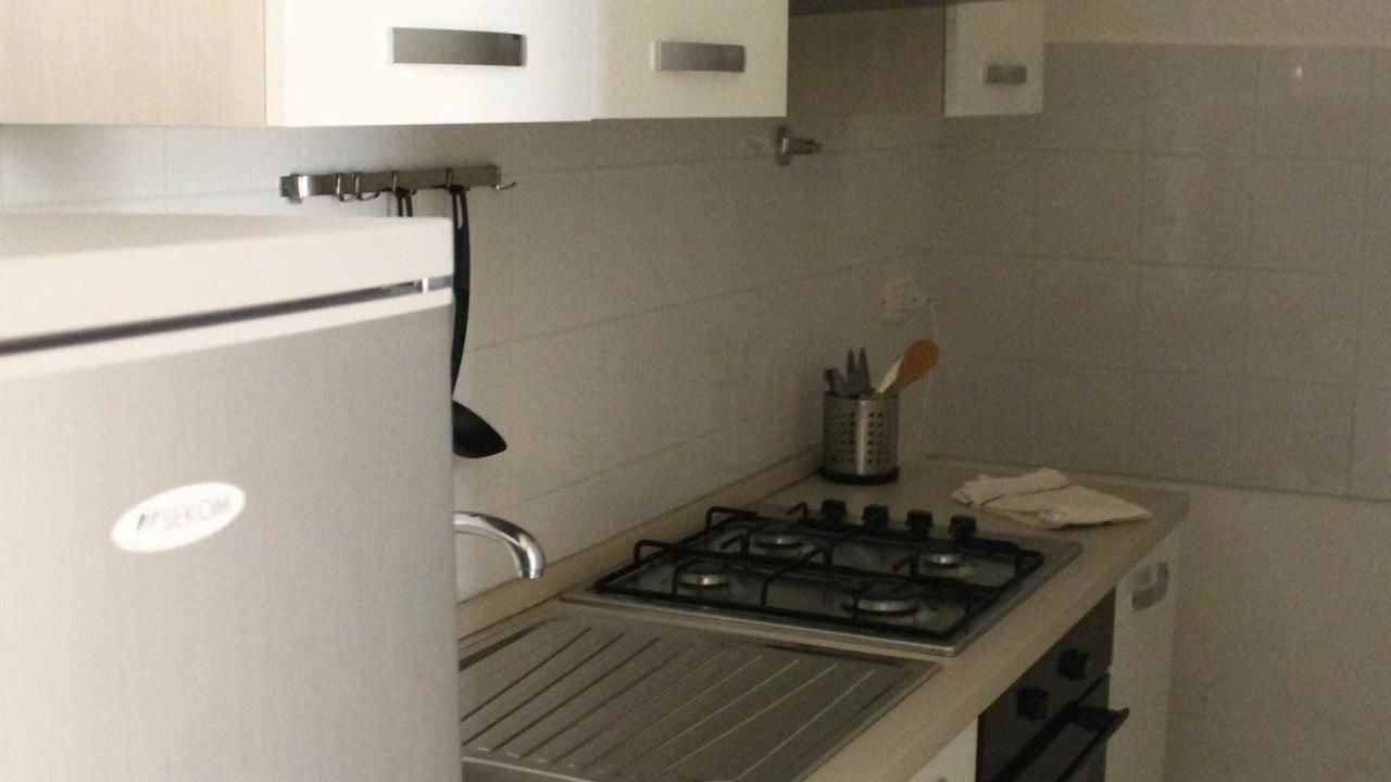 A compact kitchen with a gas stove, a sink, and a refrigerator.