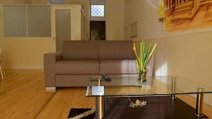 A living room with a brown sofa, a glass coffee table, and a vase with flowers. - B&B La Torretta di Chiaia (Naples)