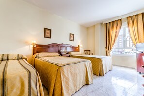 A hotel room with two beds, a wooden headboard, a nightstand, a desk, a chair, and a TV.