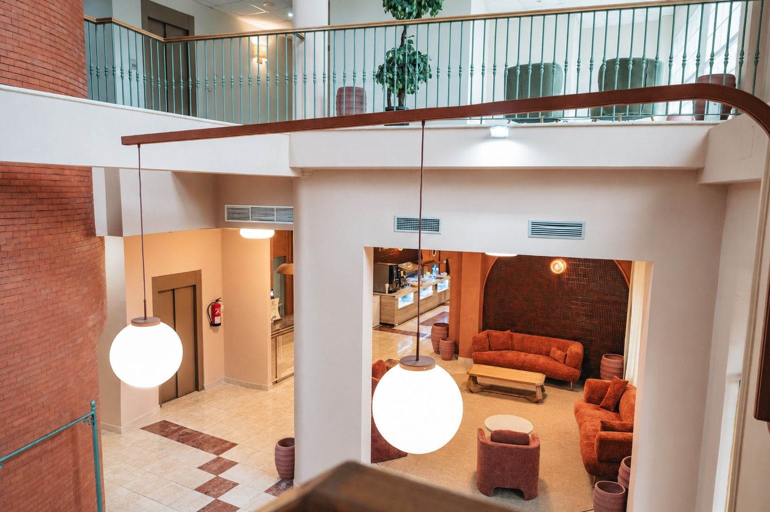 Un hall d’hôtel avec un escalier, un coin salon avec des canapés, et une cuisine visible au fond.